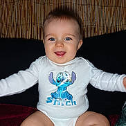 Izao participe au concours pour gagner de l'argent avec cette photo : baby, child, smiling, blue_eyes, onesie, stitch, animated_character, sitting, indoor, cushion, bamboo_wall, happy, cute, portrait, infant, clothing, person, face, expression, long_sleeve