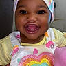 baby, child, smiling, headband, colorful_clothing, heart_pattern, happy, portrait, indoors, cute, infant, person, closeup, adorable, young_child, face, fashion, sequin, yellow_shirt, pink