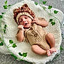 baby, infant, knitted_clothing, lion_hat, blanket, ivy_leaves, cute, sleeping, cozy, soft, portrait, child, newborn, resting, indoor, baby_feet, baby_hands, warm_colors, texture, adorable