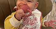 Alanna Salcedo is registered to the contest to win money with this photo: baby, infant, child, smiling, sitting, high_chair, teething_toy, pacifier, bib, yellow_outfit, floral, roses, hand, earring, indoor, kitchen, chair, portrait, happy, home
