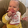 baby, infant, child, smiling, sitting, high_chair, teething_toy, pacifier, bib, yellow_outfit, floral, roses, hand, earring, indoor, kitchen, chair, portrait, happy, home