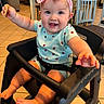 baby, child, high_chair, smiling, headband, bow, cracker, indoor, dining_area, chair, floor_tiles, cute, reaching, happy, person, infant, clothing, seated, furniture, table