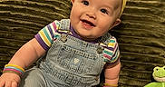 Eleonor is registered to the contest to win money with this photo: baby, bracelets, child, colorful, cute, green_couch, happy, headband, indoor, infant, overalls, person, playful, plush, portrait, sitting, smiling, striped_shirt, toy, young