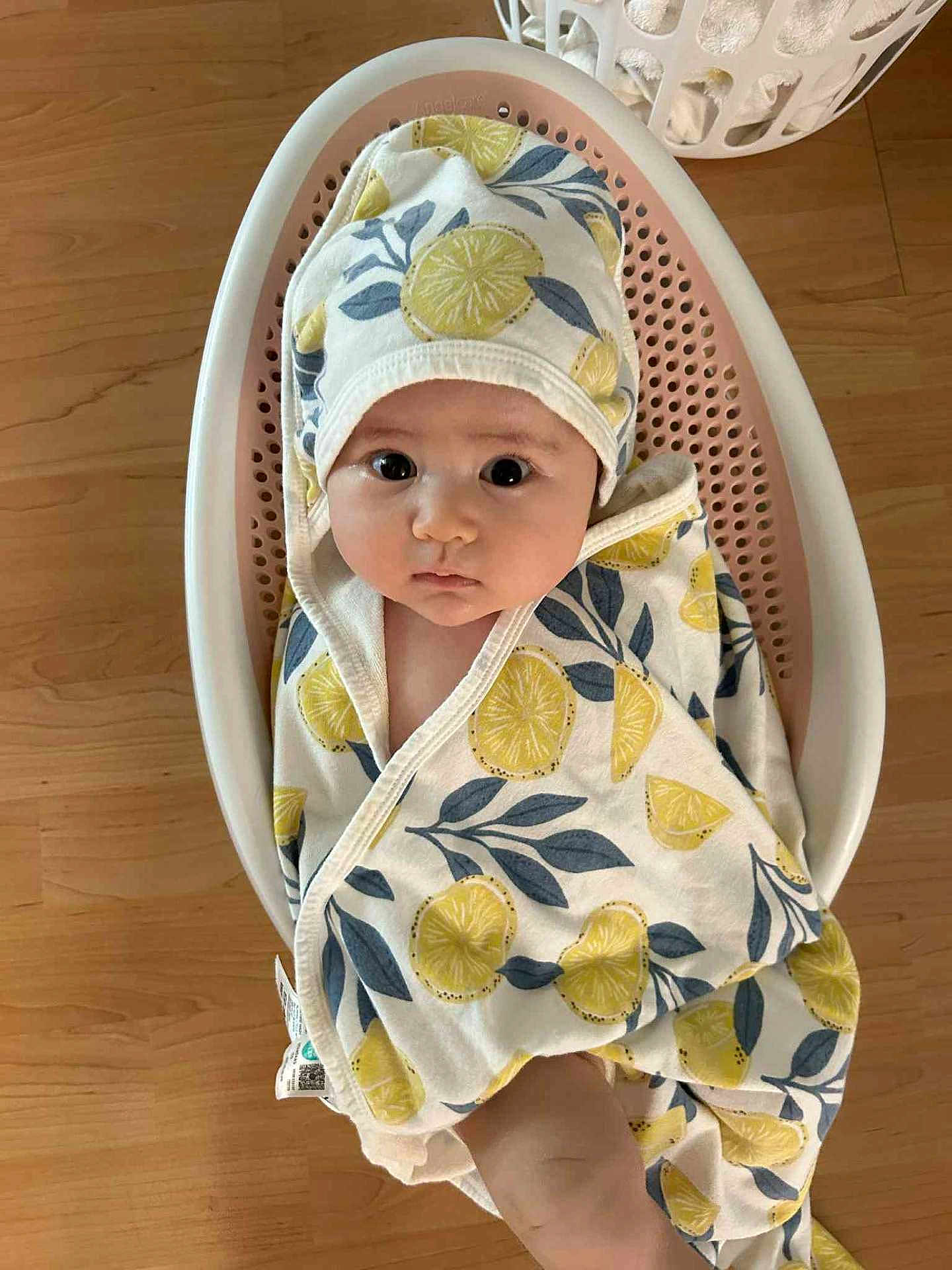 Hanna is registered to the contest to win money with this photo: baby, infant, towel, hooded_towel, lemon_pattern, bath_seat, wooden_floor, wrapped, cute, child, young, indoors, looking_up, expression, soft, comfortable, skin, face, eyes, person