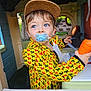 blue_eyes, cap, casual_clothing, child, colorful, curious, cute, expression, hat, horse_pattern, indoor, pacifier, person, play, playhouse, portrait, toddler, toy_carrot, yellow_jacket, young_child