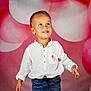 Tom a rejoint le concours — aidez-le/la à gagner de superbes lots ! child, toddler, boy, smiling, white_shirt, pink_ribbon, blue_jeans, standing, balloons, pink_background, portrait, cute, happy, casual_clothing, indoor, celebration, colorful, young_child, fashion, looking_up