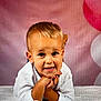 child, toddler, smiling, white_shirt, blond_hair, face, portrait, hands, blanket, balloons, pink_background, cute, happy, indoors, baby, expression, lying_down, celebration, studio, young