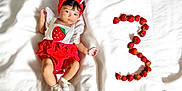 Raikishori is registered to the contest to win money with this photo: baby, infant, strawberry, red_headband, white_blanket, number_three, fruit, fresh_strawberries, cute, milestone, baby_clothing, portrait, lying_down, headband, socks, bracelet, child, colorful, celebration, soft_texture
