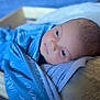 James is registered to the contest to win money with this photo: baby, blanket, blue, cushion, face, infant, newborn, person, portrait, resting, soft, wrapped, young, indoors, skin, head, eyes, sleepy, cozy, closeup