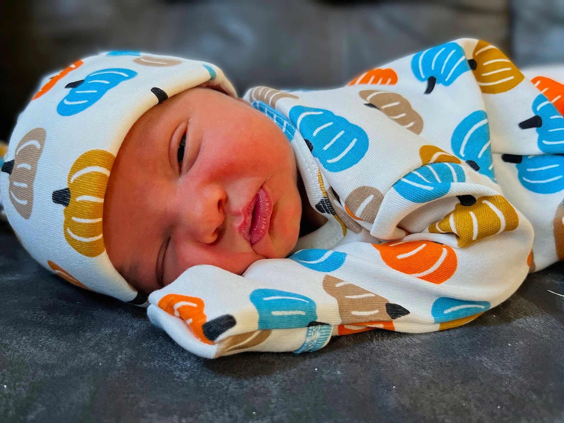 James is registered to the contest to win money with this photo: newborn, baby, sleeping, infant, cozy, hat, clothing, patterned, pumpkin, cute, soft, portrait, resting, child, young, wrapped, warm, face, peaceful, indoors