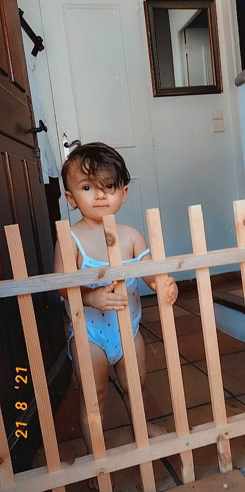 Seyana participe au concours pour gagner de l'argent avec cette photo : child, elbow, flooring, fun, handrail, hardwood, house, human_body, human_leg, knee, leg, leisure, person, shorts, sitting, stairs, thigh, toddler, waist, window