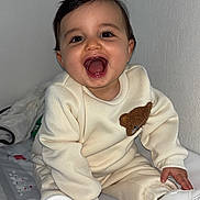 Tilyano a rejoint le concours — aidez-le/la à gagner de superbes lots ! baby, child, smiling, sitting, white_shoes, cream_outfit, teddy_bear_patch, patterned_mat, happy, indoors, cute, infant, young_child, clothing, footwear, person, portrait, cheerful, face, head