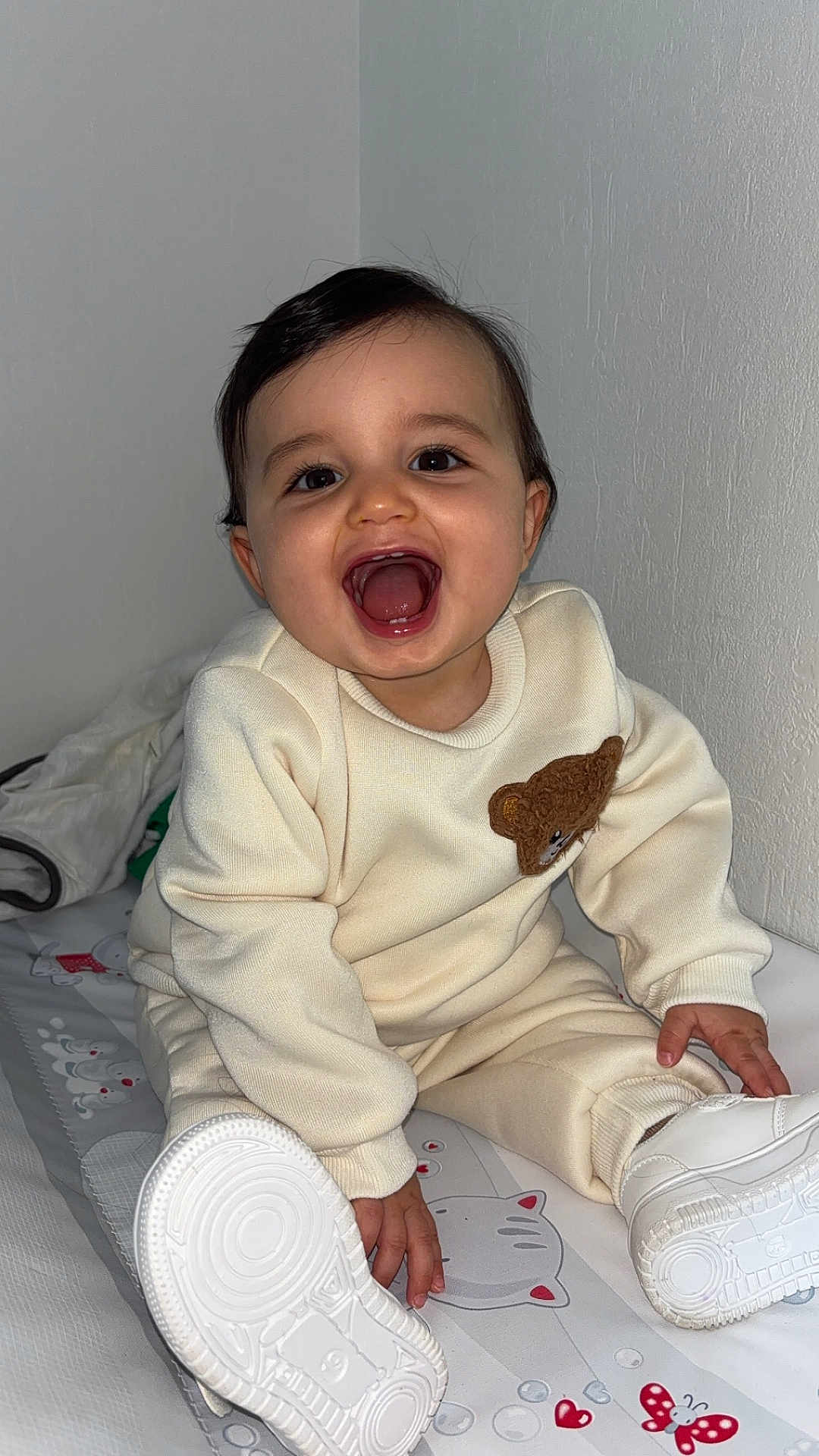 Tilyano a rejoint le concours — aidez-le/la à gagner de superbes lots ! baby, child, smiling, sitting, white_shoes, cream_outfit, teddy_bear_patch, patterned_mat, happy, indoors, cute, infant, young_child, clothing, footwear, person, portrait, cheerful, face, head