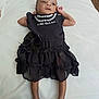 Unique joined the competition — help win amazing prizes! baby, infant, black_dress, bow, bed, white_bed, lying_down, curious, small_hands, barefoot, indoors, soft_lighting, cute, child, person, newborn, fashion, clothing, portrait, skin