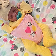 Unique joined the competition — help win amazing prizes! baby, sleeping, pacifier, hat, yellow_clothing, pink_bib, stars, hearts, blanket, polka_dots, cute, infant, cozy, soft, peaceful, child, resting, indoors, colorful, patterned