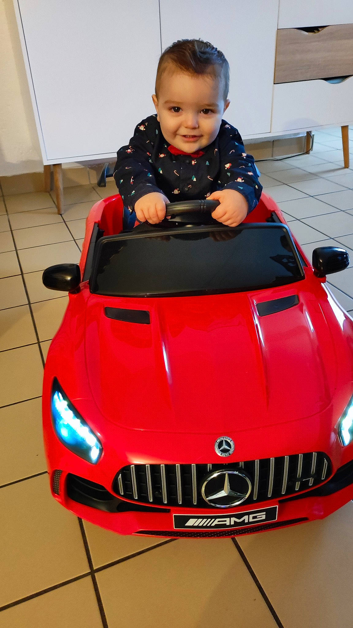 Max participe au concours pour gagner de l'argent avec cette photo : automotive_design, automotive_exterior, automotive_fog_light, automotive_lighting, bumper, car, chair, fender, grille, headlamp, hood, joy, motor_vehicle, person, personal_luxury_car, photograph, red, smile, snapshot, toddler
