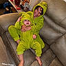 baby, child, sibling, smiling, laughing, cuddling, green_outfit, animal_costume, hooded_pajamas, infant, toddler, sitting, sofa, couch, living_room, indoor, portrait, family, watermark, side_table