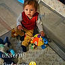 child, toddler, baby, sitting, playpen, toys, stuffed_animals, colorful, indoor, morning, portrait, face, curious, red_vest, yellow_pants, black_socks, toy_car, soft_toy, nursery, text_overlay