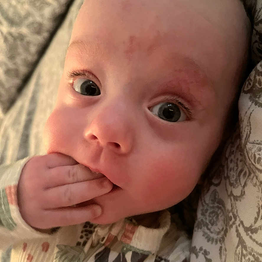 Archer is registered to the contest to win money with this photo: baby, bodypart, bonnet, clothing, face, finger, hand, happy, hat, head, mouth, newborn, person, photography, portrait, skin, smile, tattoo