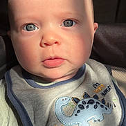 Javant joined the competition — help win amazing prizes! baby, infant, face, blue_eyes, bib, dinosaur, clothing, closeup, portrait, child, cute, soft_light, sunlight, expression, young, skin, apparel, indoors, adorable, person
