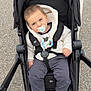 toddler, stroller, pacifier, child, clothing, sweater, hood, shoe, footwear, pavement, outdoor, baby, seat, safety_belt, wheel, cute, person, infant, casual, transport