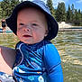 Beau joined the competition — help win amazing prizes! baby, blue_clothing, child, face, forest, happy, hat, holding, lake, nature, outdoor, person, recreation, sky, smiling, summer, sunny, swimsuit, trees, water