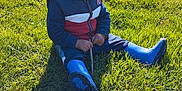Yanis participe au concours pour gagner de l'argent avec cette photo : child, toddler, grass, outdoor, boots, hoodie, stick, sunlight, backyard, greenery, casual_clothing, sitting, daylight, young_child, nature, person, playing, cute, relaxed, exploring