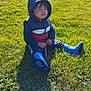 child, toddler, grass, outdoor, boots, hoodie, stick, sunlight, backyard, greenery, casual_clothing, sitting, daylight, young_child, nature, person, playing, cute, relaxed, exploring