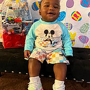 Semaj joined the competition — help win amazing prizes! toddler, child, smiling, mickey_mouse, pajamas, sneakers, bench, easter_decor, colorful_background, indoor, carpet, happy, toy, gift_basket, cute, person, portrait, sitting, playful, holiday