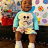 toddler, child, smiling, mickey_mouse, pajamas, sneakers, bench, easter_decor, colorful_background, indoor, carpet, happy, toy, gift_basket, cute, person, portrait, sitting, playful, holiday