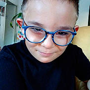 Ethan participe au concours pour gagner de l'argent avec cette photo : child, boy, glasses, smile, black_shirt, indoor, face, portrait, short_hair, young, happy, seated, houseplant, background, colorful, eyewear, casual, person, eyebrows, skin
