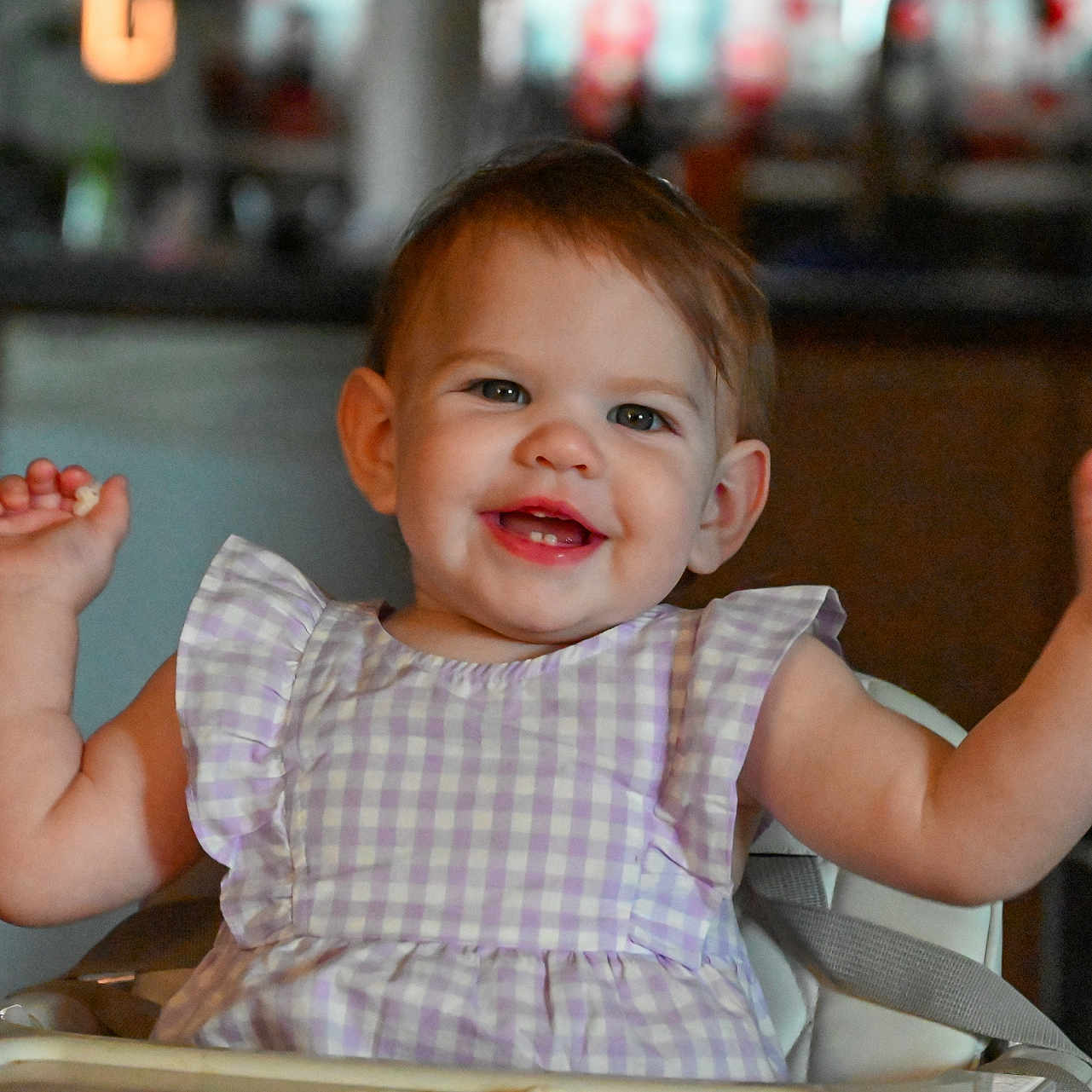 Kelsey joined the competition — help win amazing prizes! arms_raised, baby, celebration, checkered, child, cute, dress, expression, face, furniture, happy, high_chair, indoor, kitchen, person, purple, seat, smiling, toddler, young