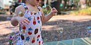 Kelsey joined the competition — help win amazing prizes! child, toddler, bubble, bubble_machine, outdoor, play, joyful, romper, colorful_clothing, summer, sandals, grass_mat, nature, trees, sunlight, happy, portrait, fun, toy, bubbles