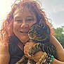 woman, cat, pet, outdoor, smiling, red_hair, curly_hair, bracelets, tabby_cat, holding, affection, nature, greenery, portrait, animal, happy, closeup, feline, friendship, skin