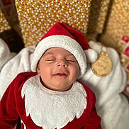Nahyl a rejoint le concours — aidez-le/la à gagner de superbes lots ! baby, smiling, santa_hat, christmas_outfit, red_clothing, white_beard, infant, sleeping, blanket, cushion, holiday, festive, cute, child, portrait, soft_texture, indoor, resting, happy, celebration