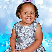 Ariel-Lee is registered to the contest to win money with this photo: toddler, child, smiling, portrait, dress, silver_dress, curly_hair, bow, happy, studio_background, blue_bokeh, cute, young_child, fashion, formal_wear, person, photography, baby, hands, sitting