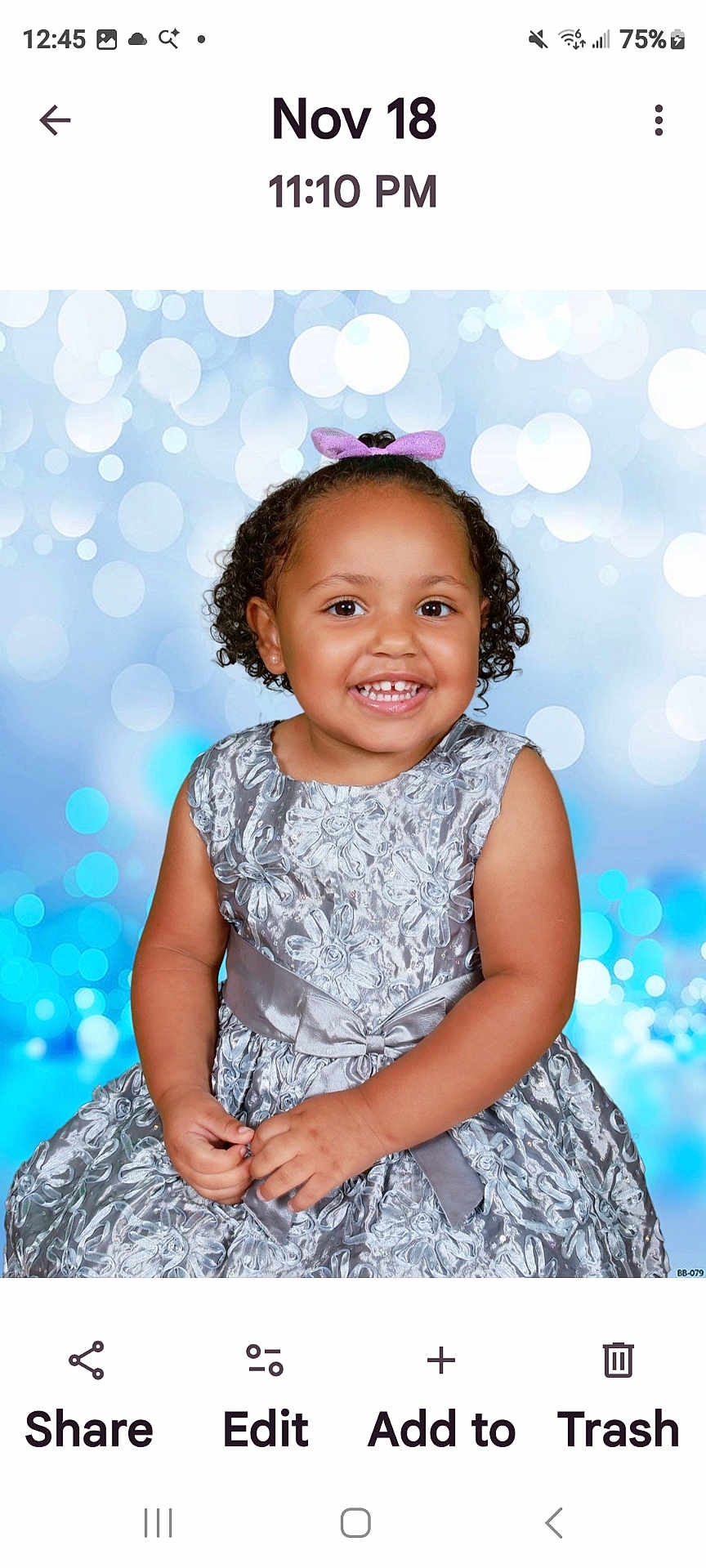 Ariel-Lee is registered to the contest to win money with this photo: toddler, child, smiling, portrait, dress, silver_dress, curly_hair, bow, happy, studio_background, blue_bokeh, cute, young_child, fashion, formal_wear, person, photography, baby, hands, sitting
