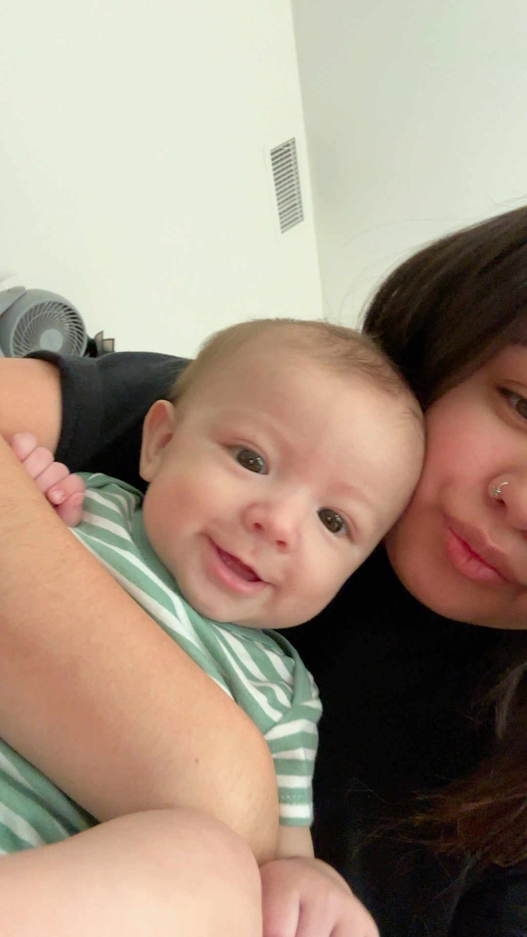 Sebastian is registered to the contest to win money with this photo: baby, child, woman, person, smile, face, arm, hair, striped_clothing, holding, indoor, skin, head, nose_ring, happy, closeup, affection, family, love, portrait