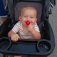 Kinzley is registered to the contest to win money with this photo: baby, child, clothing, colorful, cute, daylight, fun, happy, lollipop, outdoor, people, person, playful, seat, smiling, stroller, summer, toddler, toy, young
