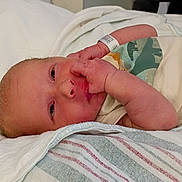 Justin is registered to the contest to win money with this photo: baby, bed, blanket, child, closeup, cute, dinosaur, face, hand, hospital, infant, lying_down, newborn, onesie, peaceful, person, skin, sleepy, soft, wristband