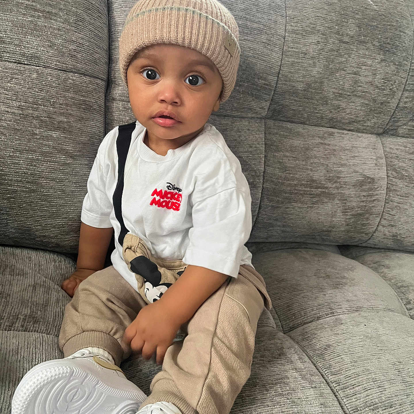 Blair-Ryser joined the competition — help win amazing prizes! beanie, beige_pants, big_eyes, casual_clothing, child, couch, cute, hat, indoor, living_room, mickey_mouse, portrait, sitting, sneakers, sofa, surprised_expression, textured_sofa, toddler, white_sneakers, white_tshirt