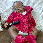 Messiah joined the competition — help win amazing prizes! baby, blanket, child, couch, cozy, cute, furniture, glasses, home, indoor, infant, person, red_booties, red_robe, relaxed, remote_control, resting, sleeping, soft, wearing