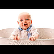 Jayce is registered to the contest to win money with this photo: baby, infant, smiling, happy, face, hands, white_tub, clothing, blue_collar, cute, child, portrait, studio, bright_background, isolated, sitting, young, skin, head, expression