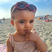 Mélina joined the competition — help win amazing prizes! toddler, child, beach, sunglasses, sand, sunlight, sky, person, outdoor, casual_clothing, curious, finger_in_mouth, summer, vacation, portrait, cute, young_child, bare_arms, daylight, relaxation