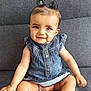 arm, baby, casual_clothing, child, couch, cute, denim_dress, face, hair_buns, happy, indoor, infant, legs, person, portrait, sitting, skin, smiling, toddler, young_child