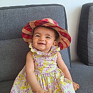 Mélina a rejoint le concours — aidez-le/la à gagner de superbes lots ! toddler, child, smiling, hat, floral_dress, sitting, couch, indoor, happy, portrait, cute, baby, face, person, furniture, colorful, pattern, young_child, casual, cheerful