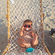 Mélina participe au concours pour gagner de l'argent avec cette photo : baby, beach, child, cute, foot, hammock, infant, netting, outdoor, pacifier, playful, relaxation, sand, shadow, summer, sunglasses, sunlight, toy, vacation, wooden_frame