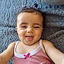 Mélina participe au concours pour gagner de l'argent avec cette photo : baby, child, smiling, tongue_out, hair_ties, pink_tank_top, blanket, texture, cute, infant, playful, lying_down, portrait, close_up, happy, indoor, person, young_child, apparel, fabric