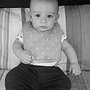 Rowdie joined the competition — help win amazing prizes! baby, child, infant, bib, clothing, pants, quilt, pattern, face, eyes, sitting, indoors, portrait, black_and_white, expression, cute, young, person, head, hand