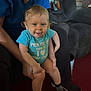 Charlie is registered to the contest to win money with this photo: toddler, child, baby, smiling, indoor, person, blue_onesie, sitting, carpet, furniture, couch, sock, legs, hand, face, expression, cute, happy, adult, holding